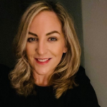 A smiling woman with shoulder-length blonde hair posing for a headshot for the fire fighters charity fundraising team.