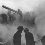 A group of people wearing helmets work amid heavy smoke and debris, likely during a fire or a wartime emergency, with one person lifting a large plank. The atmosphere appears chaotic and tense.
