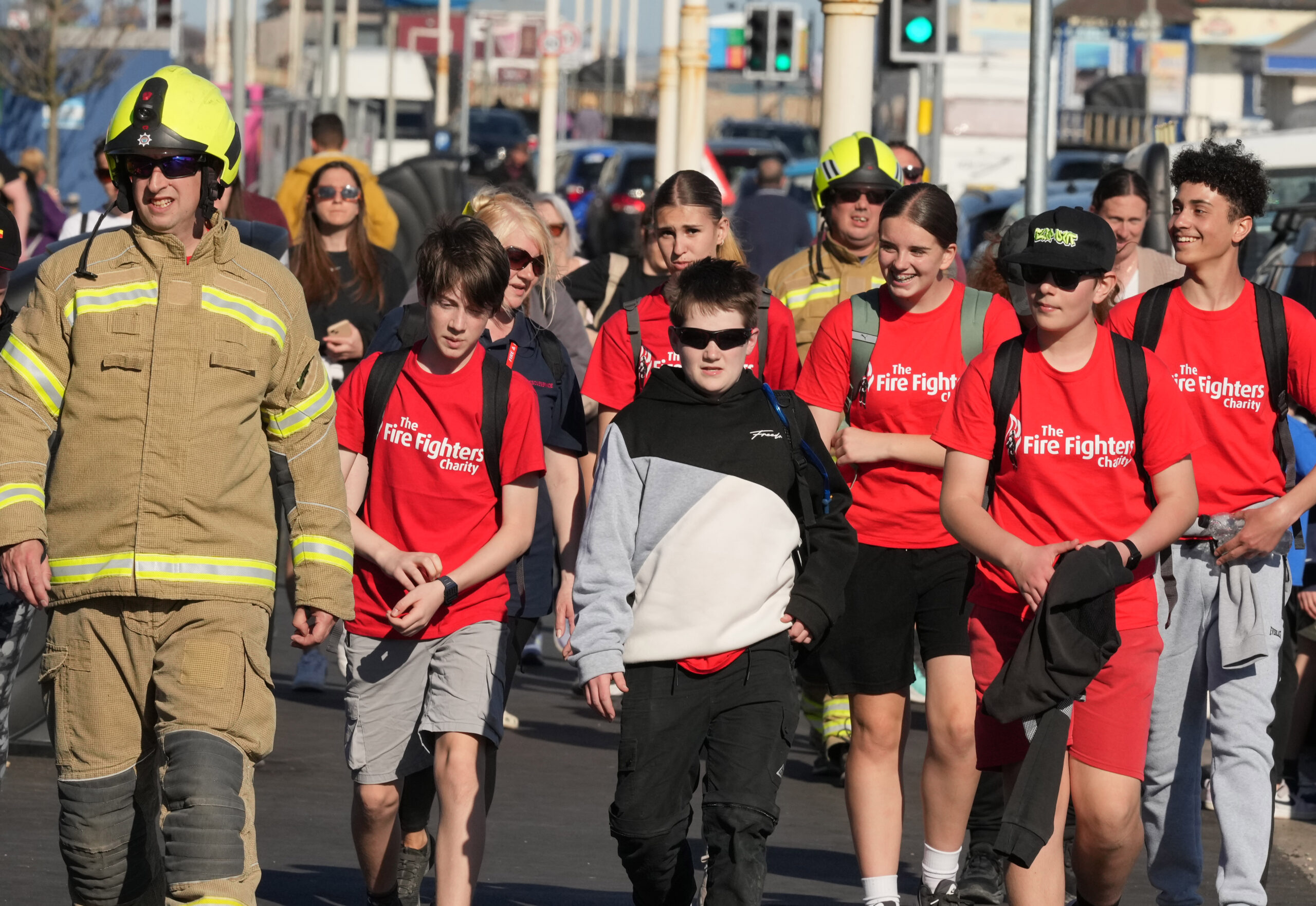 A group of people, including firefighters in uniform and youths in red