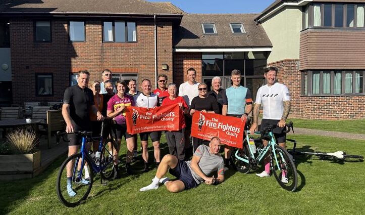A group of people poses with bicycles and two red