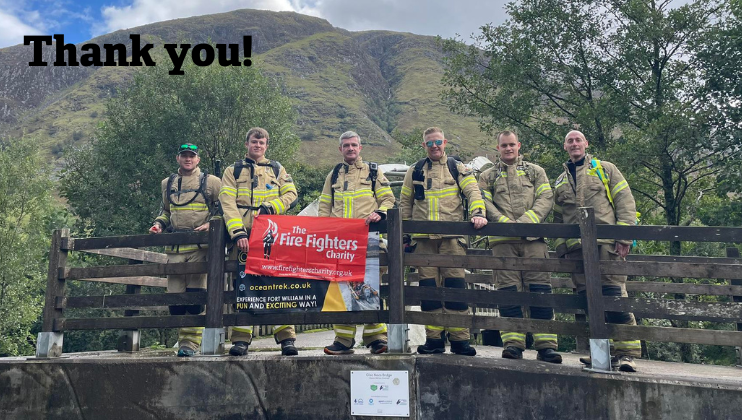Six firefighters in uniform stand on a wooden bridge with a 