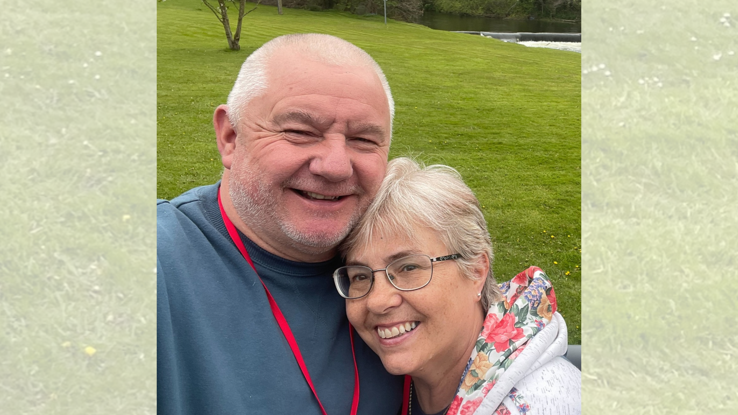 A middle-aged man and woman smiling together for a selfie outdoors.