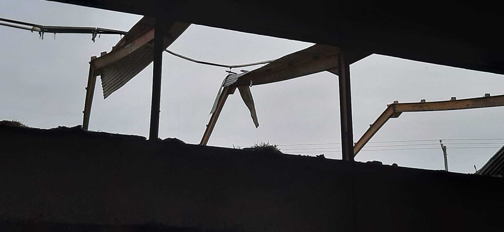Damaged structural steel beams of a building frame viewed against a cloudy sky.